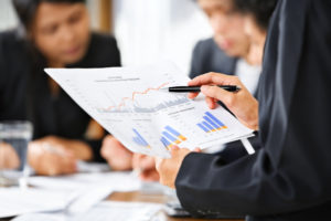 Businesswoman examining graphs with other working people on background